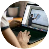 Alumne seguint una tutoria en directe del curs online de PER d'Escola Port, amb explicacions a la pissarra digital.