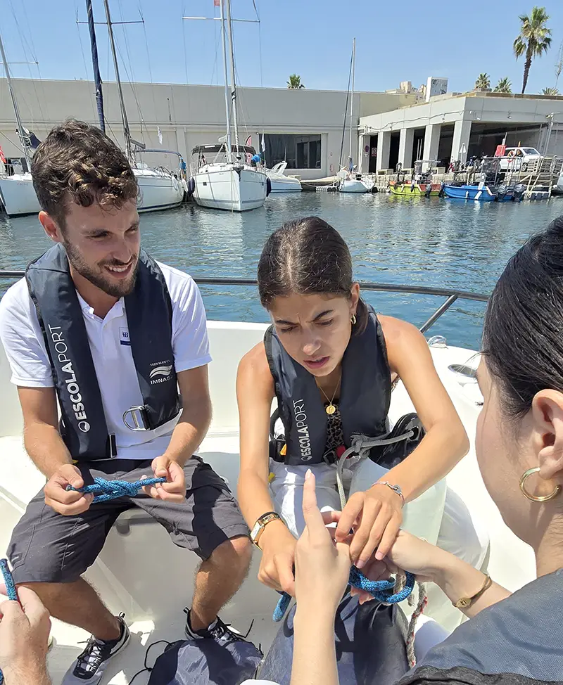 Instructor de prácticas de Licencia de navegación explicando a los alumnos cómo hacer nudos náuticos en Escola Port. Instructor de prácticas de Licencia de navegación explicando a los alumnos cómo hacer nudos náuticos en Escola Port.