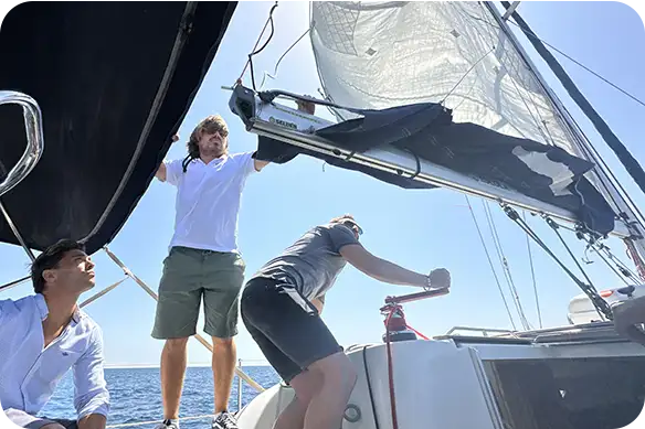 Alumnado de la Escola Port practicando maniobras de navegación a vela en un velero en el Port Olímpic de Barcelona
