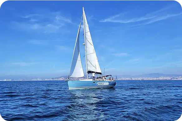 Velero de la Escola Port navegando a vela delante de Barcelona durante las prácticas de navegación a vela