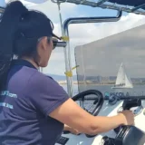Alumna al timó durant les pràctiques de la llicència de navegació al Port Olímpic