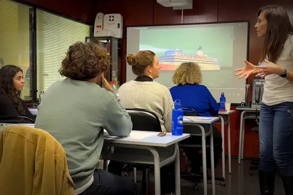 Clase del Operador restringido del SMSSM: la instructora explica una comunicación con un barco en pantalla y el grupo escuchando.