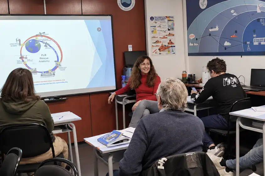 Clase de teoría del Operador restringido del SMSSM: la instructora explica cómo funciona el rescate por satélite, con el mapa de zonas en la pared.